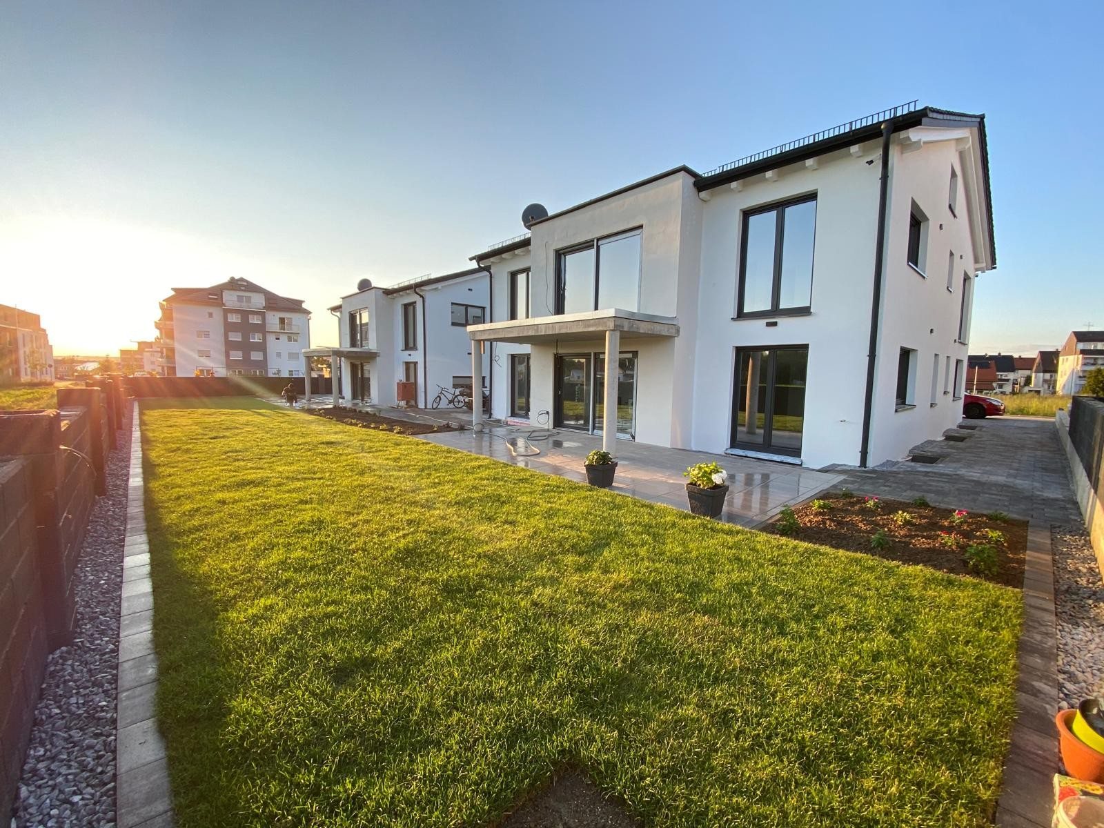 Moderne Neubauhäuser mit gepflegter Gartenanlage bei Sonnenlicht